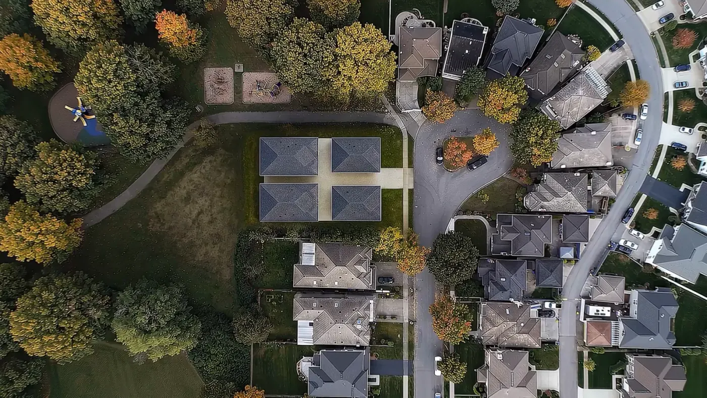 Aerial drone view of 7609 Coldicutt in Burnaby, four detached strata homes arranged in two pairs on a single cul-de-sac lot beside a park, surrounded by single-family houses